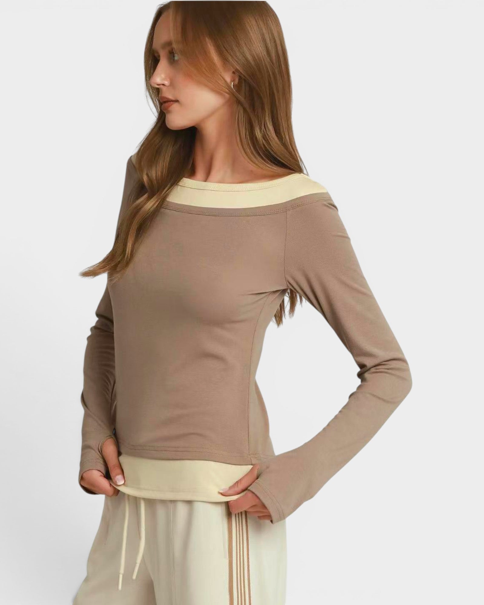 Woman wearing a brown long-sleeve top with a white trim on a light gray background