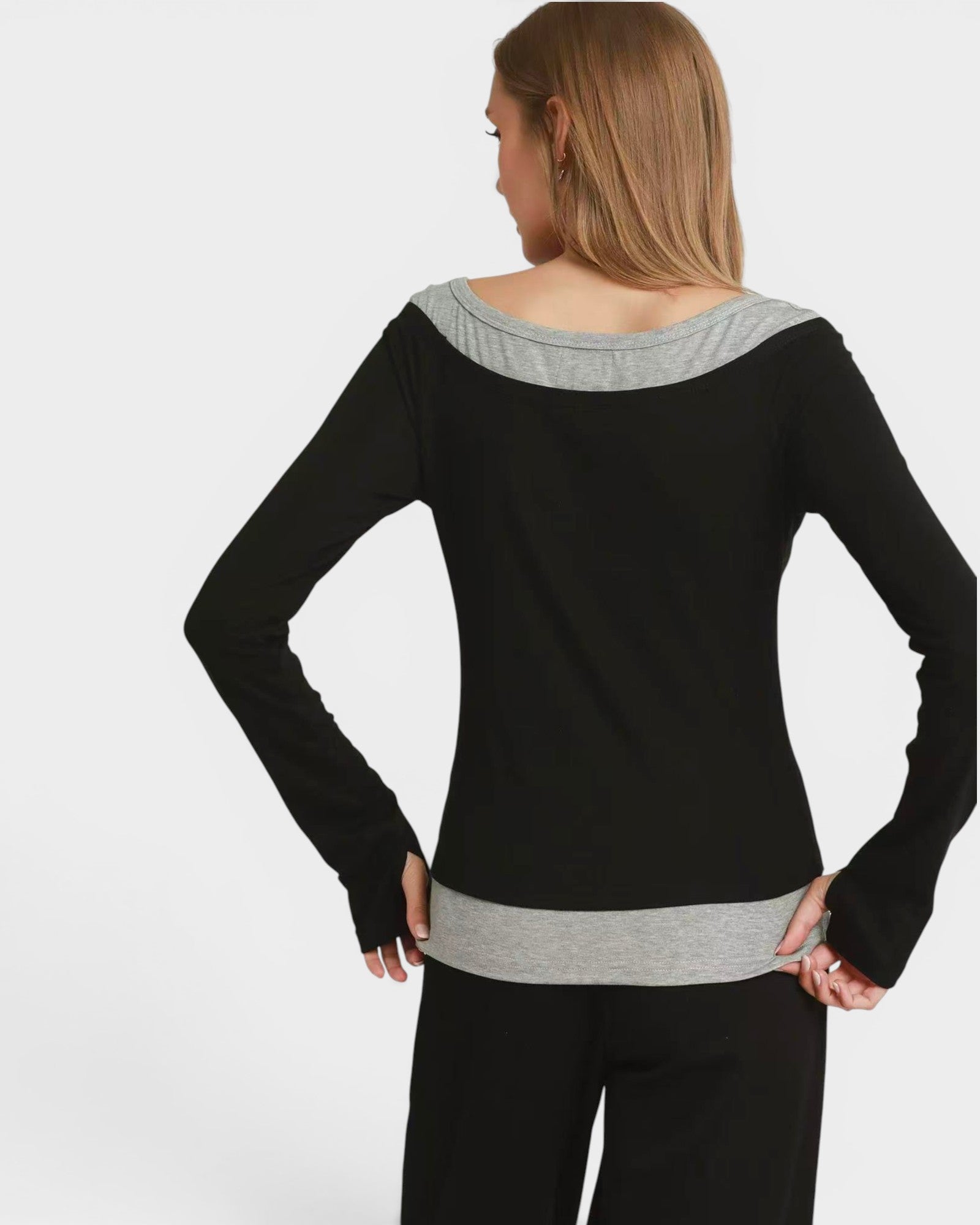 Woman wearing a black and gray top with a plain background