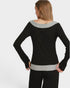Woman wearing a black and gray top with a plain background