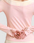 Person wearing a light pink long-sleeve top with a plain background