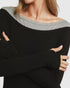 Person wearing a black and gray long-sleeve top with arms crossed.