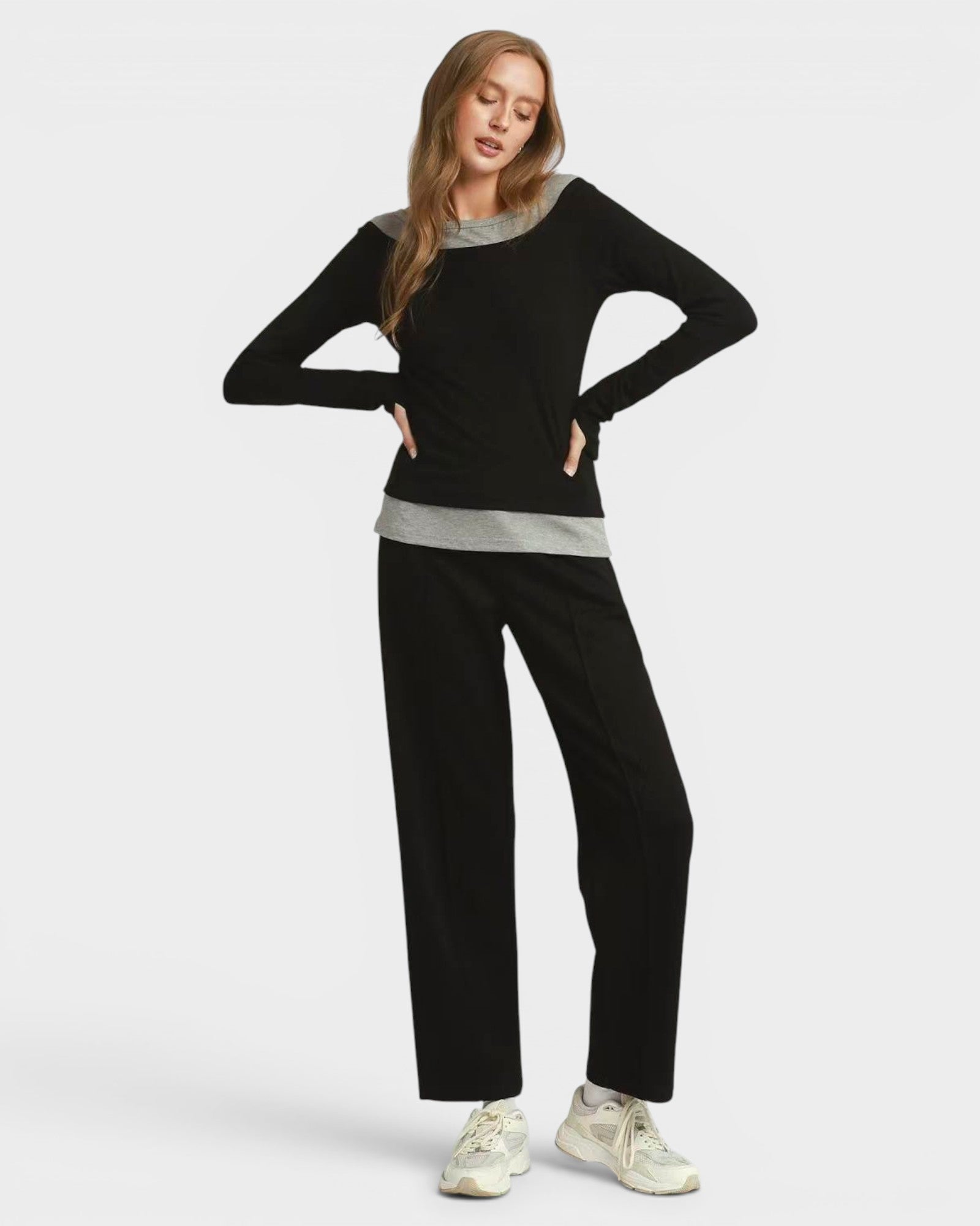Woman wearing a black sweater and pants with a gray shirt underneath on a white background