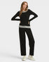 Woman wearing a black sweater and pants with a gray shirt underneath on a white background
