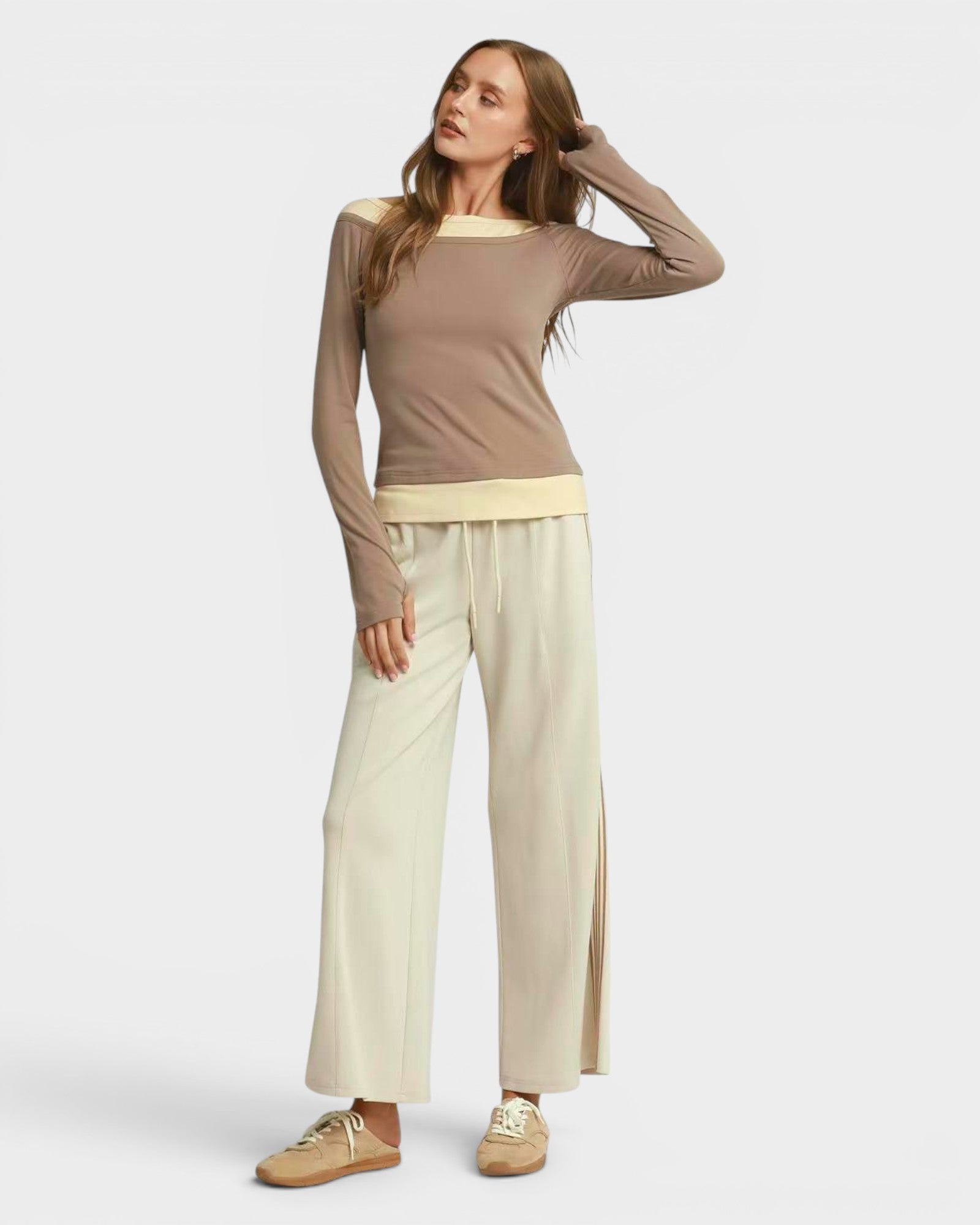 Woman wearing a brown top and beige pants on a white background