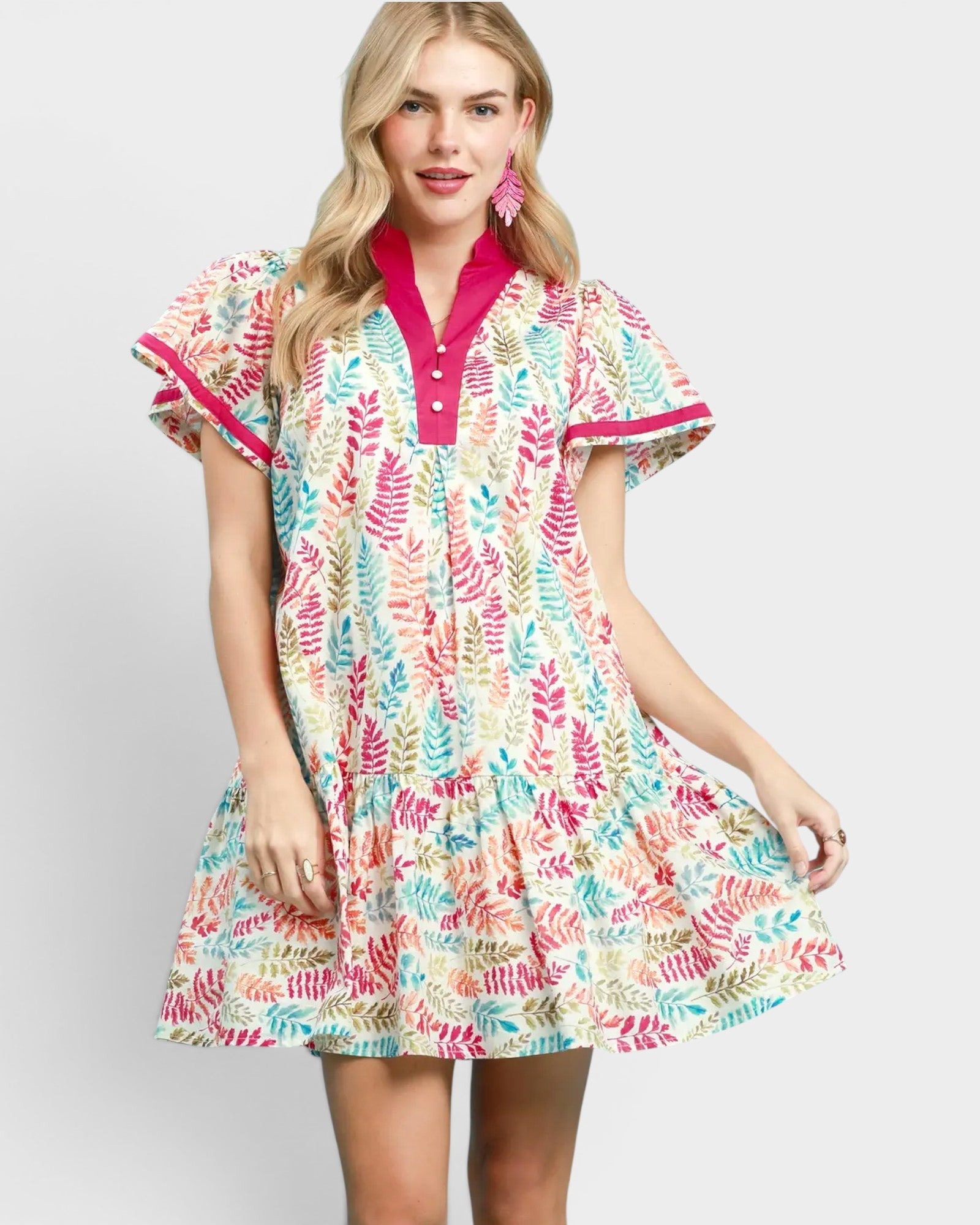 Woman wearing a colorful patterned dress with a pink collar on a white background