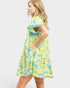 Woman wearing a colorful dress with a leaf pattern on a white background