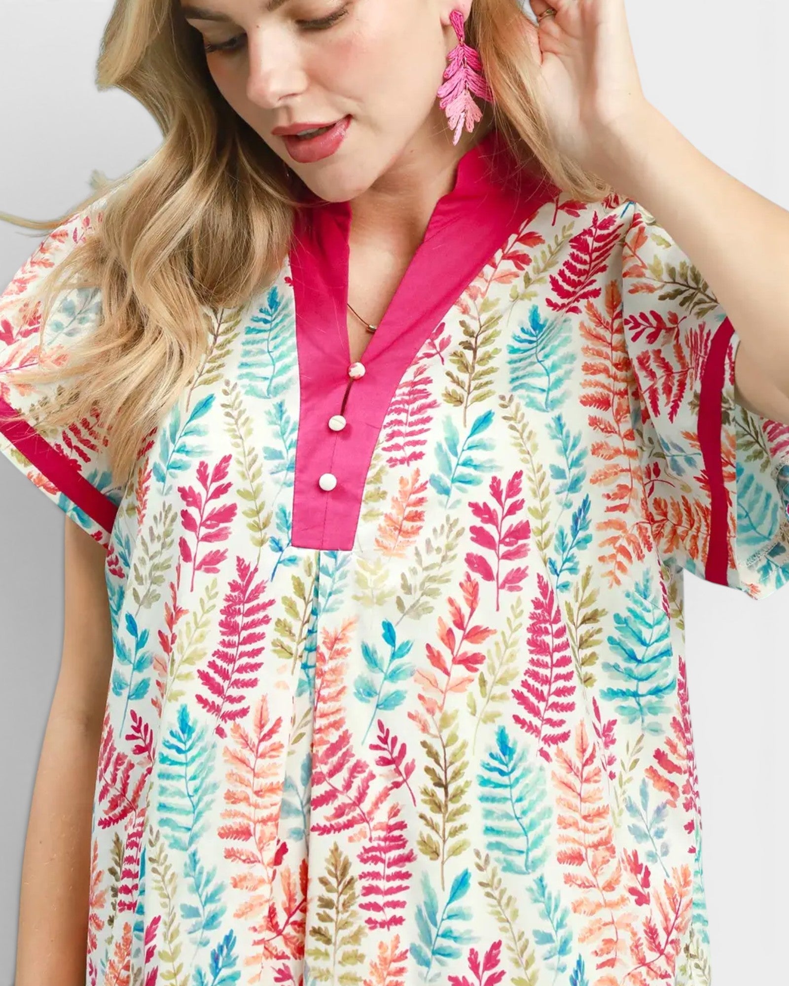 Woman wearing a colorful leaf-patterned shirt with a pink collar.