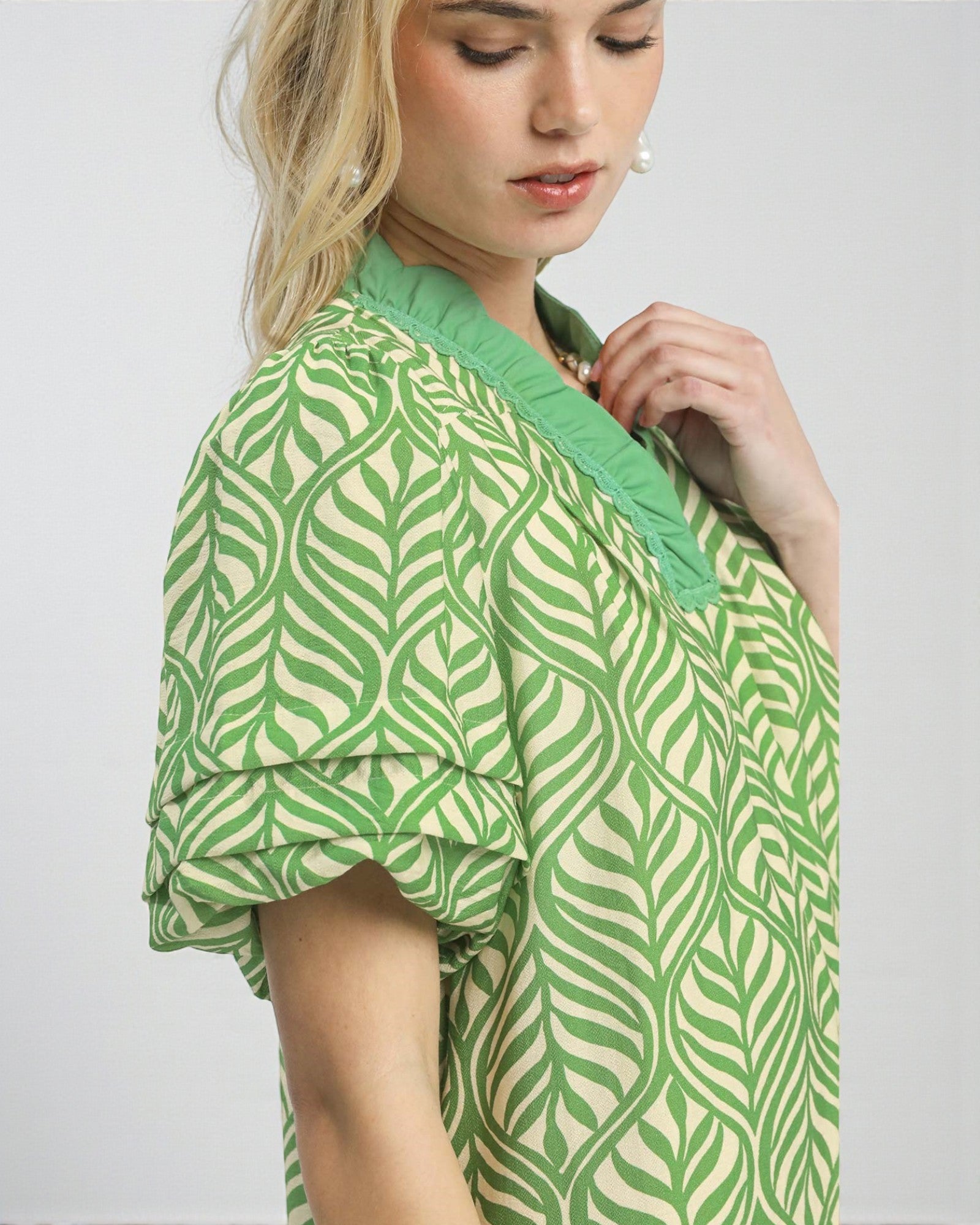 Woman wearing a green and white patterned dress against a plain background