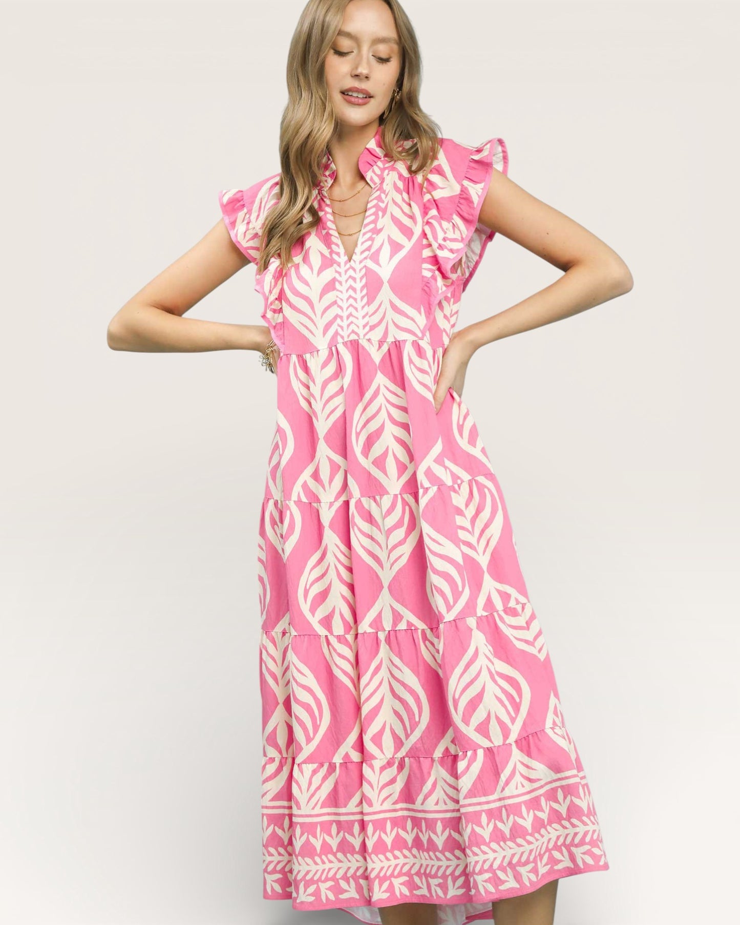 Woman wearing a pink dress with white leaf pattern on a plain background