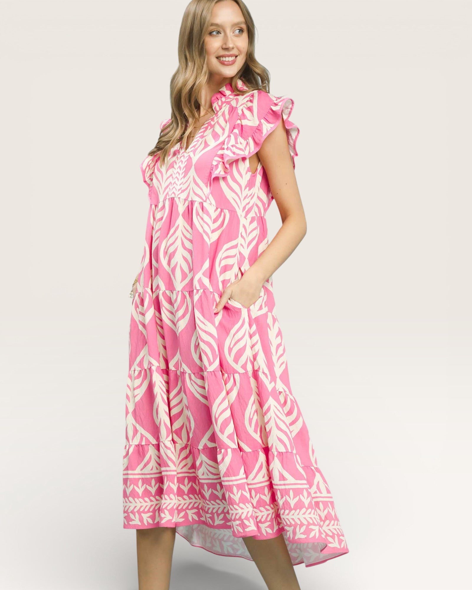 Woman wearing a pink dress with white patterns on a plain background