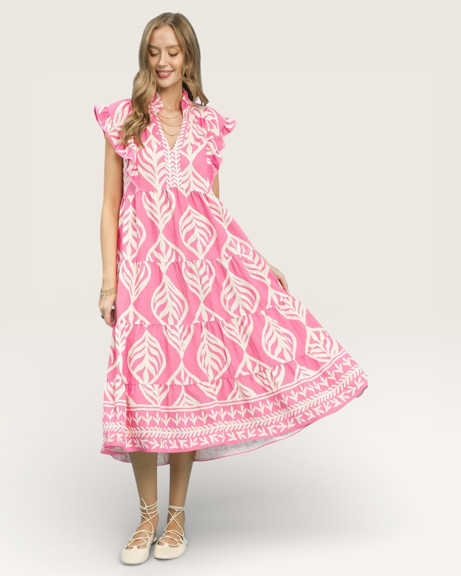 Woman wearing a pink dress with white patterns on a white background