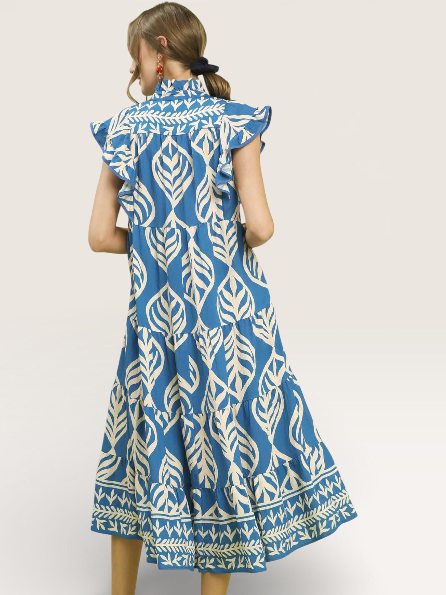 Woman wearing a blue and white patterned dress on a plain background