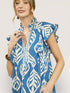 Woman wearing a blue dress with white pattern against a plain background