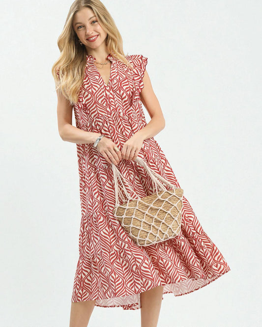 Woman wearing a red and white patterned dress holding a straw bag on a white background