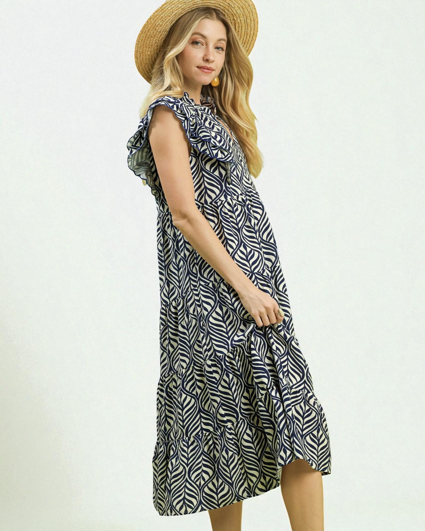 Woman wearing a patterned dress and straw hat on a white background