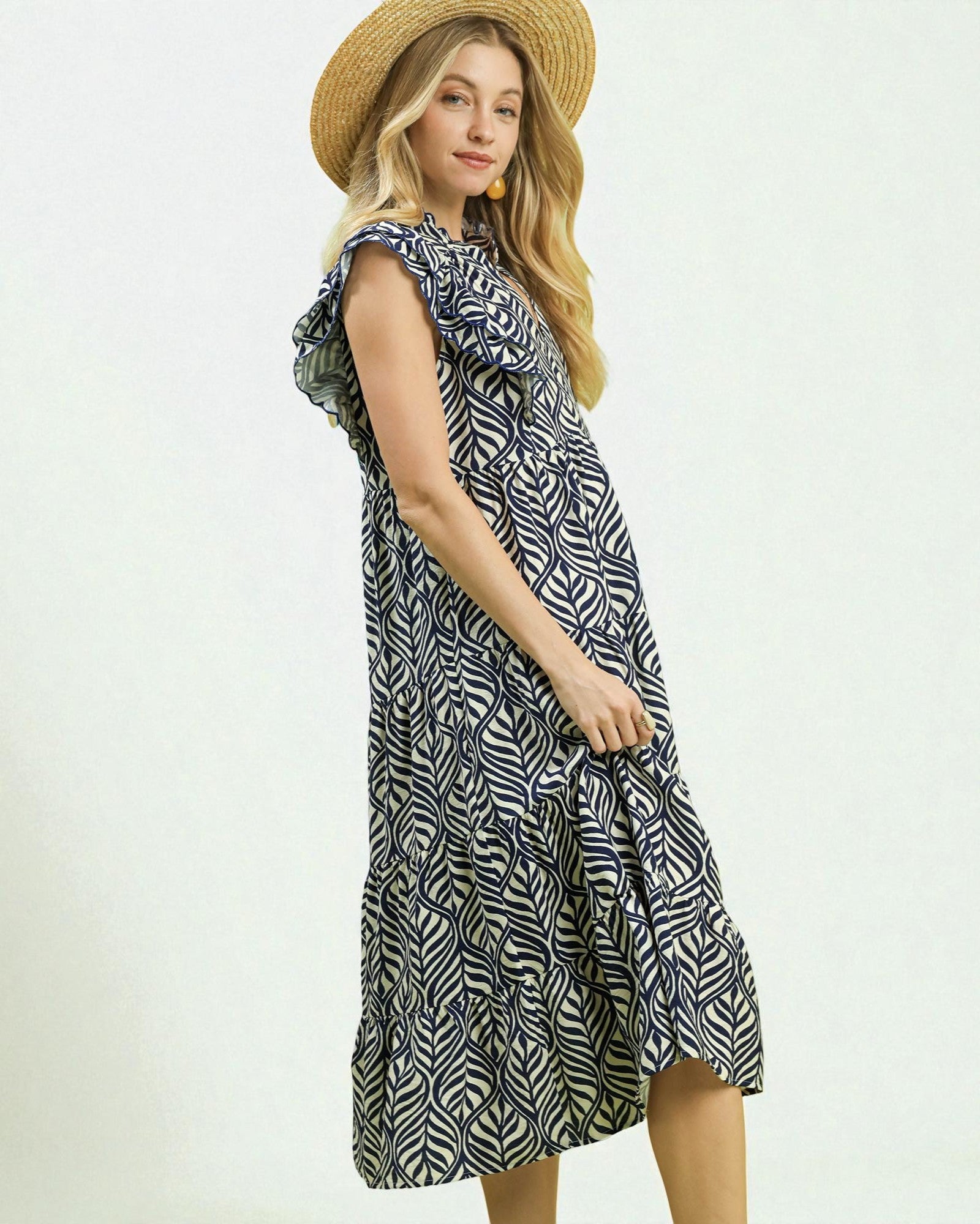 Woman wearing a patterned dress and straw hat on a white background