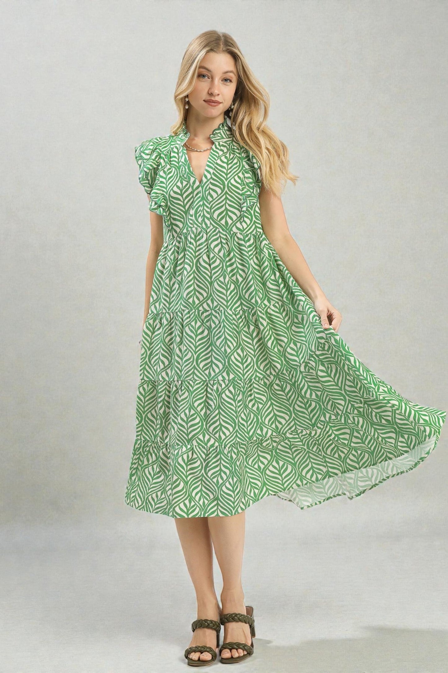 Woman wearing a green patterned dress on a plain background