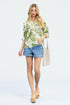 Woman wearing a floral shirt, denim shorts, and sandals on a white background