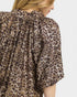 Leopard print blouse worn by a person on a plain background