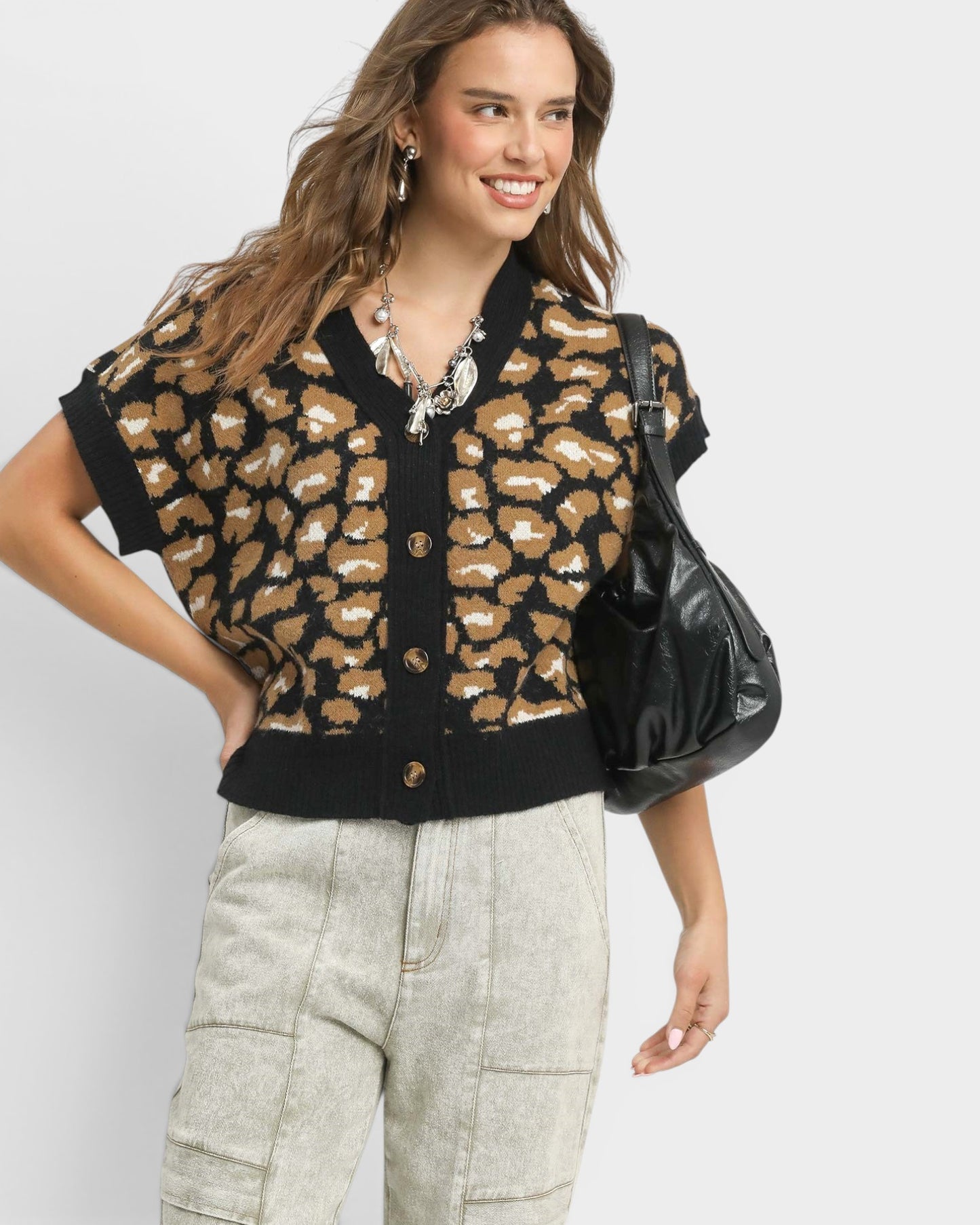 Woman wearing a leopard print cardigan with a plain background