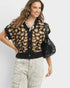 Woman wearing a leopard print cardigan with a plain background