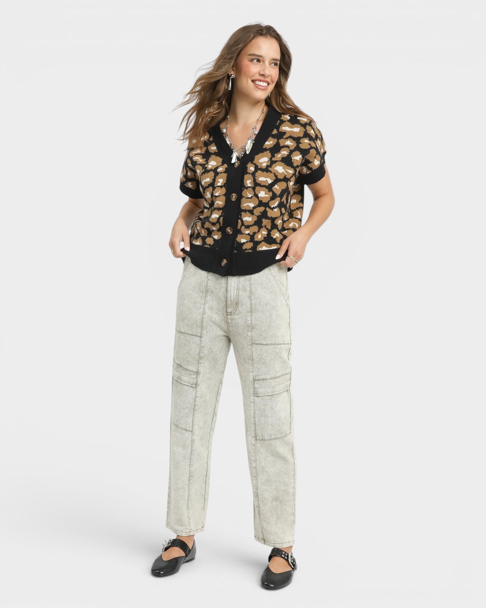 Woman wearing a patterned shirt and light pants on a white background