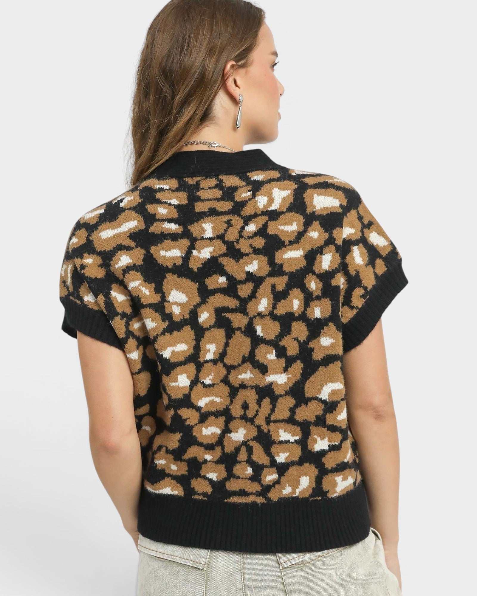 Person wearing a leopard print sweater on a plain background