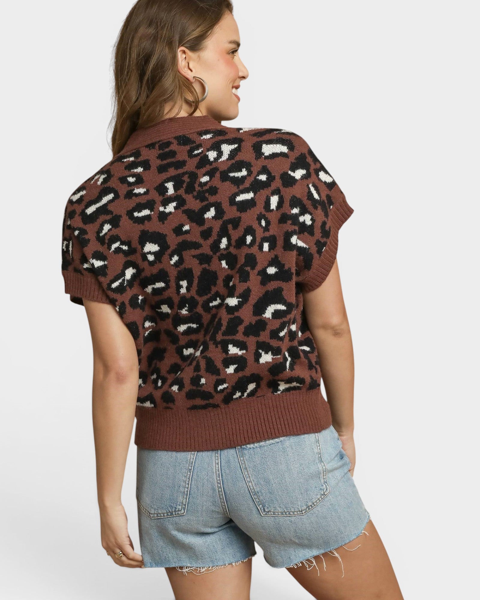 Woman wearing a leopard print sweater and denim shorts on a white background