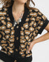 Person wearing a leopard print cardigan with a neutral background