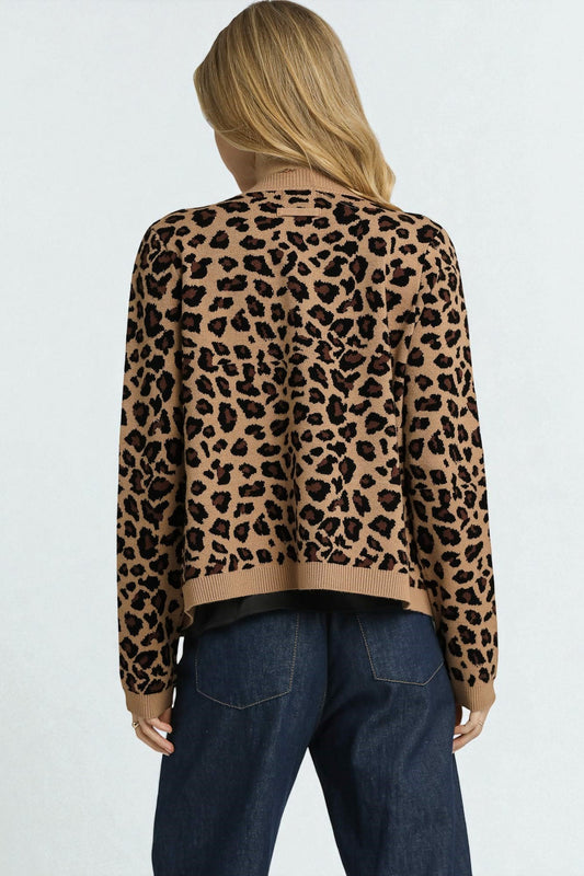 Person wearing a leopard print sweater and blue jeans on a light gray background