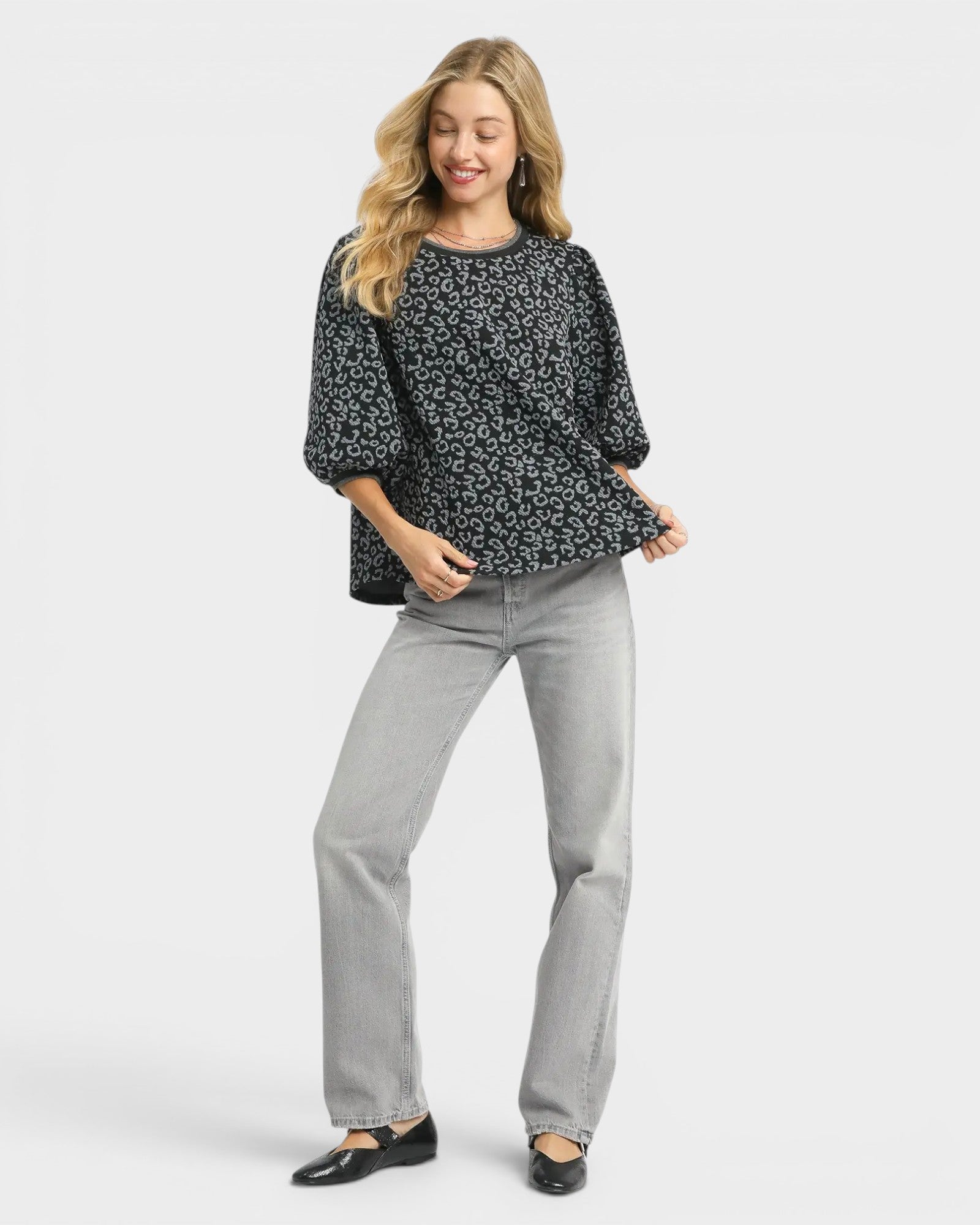 Woman wearing a black floral top and gray pants on a white background