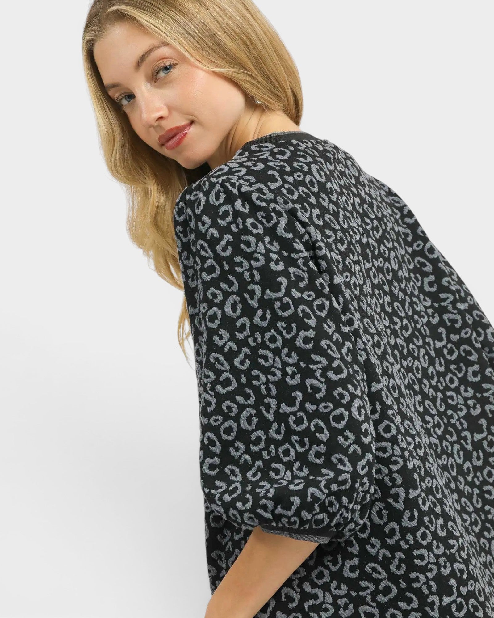 Woman wearing a dark gray cardigan with a subtle pattern on a white background