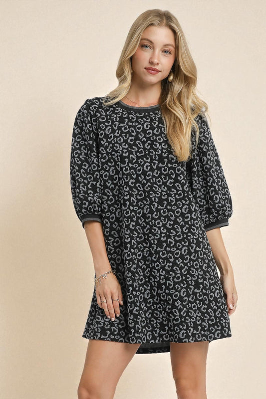 Woman wearing a black patterned dress on a beige background