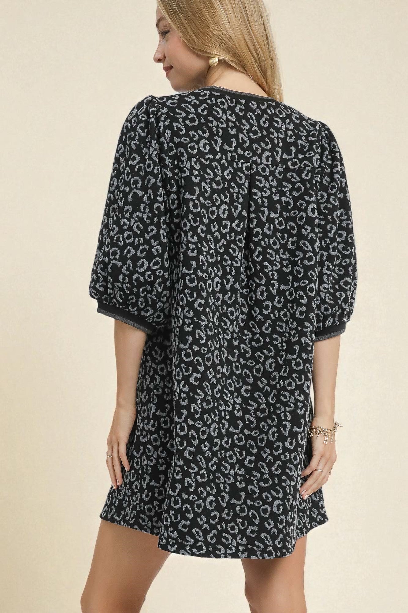 Woman wearing a black dress with white leopard print on a beige background