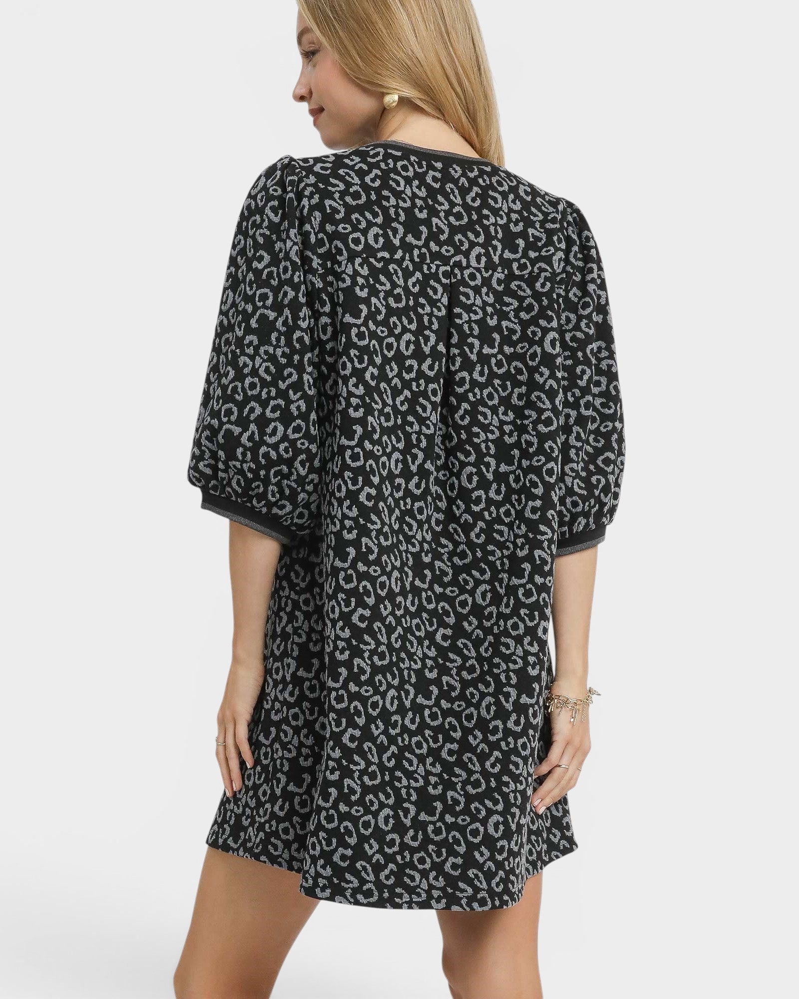 Woman wearing a black dress with white pattern on a white background