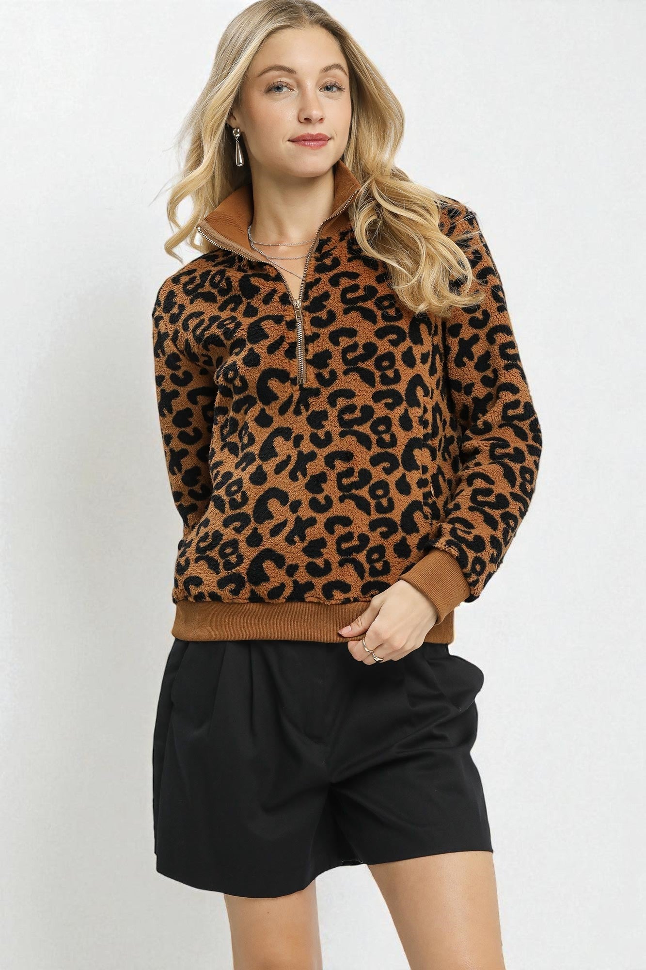Woman wearing a leopard print sweater and black shorts on a white background