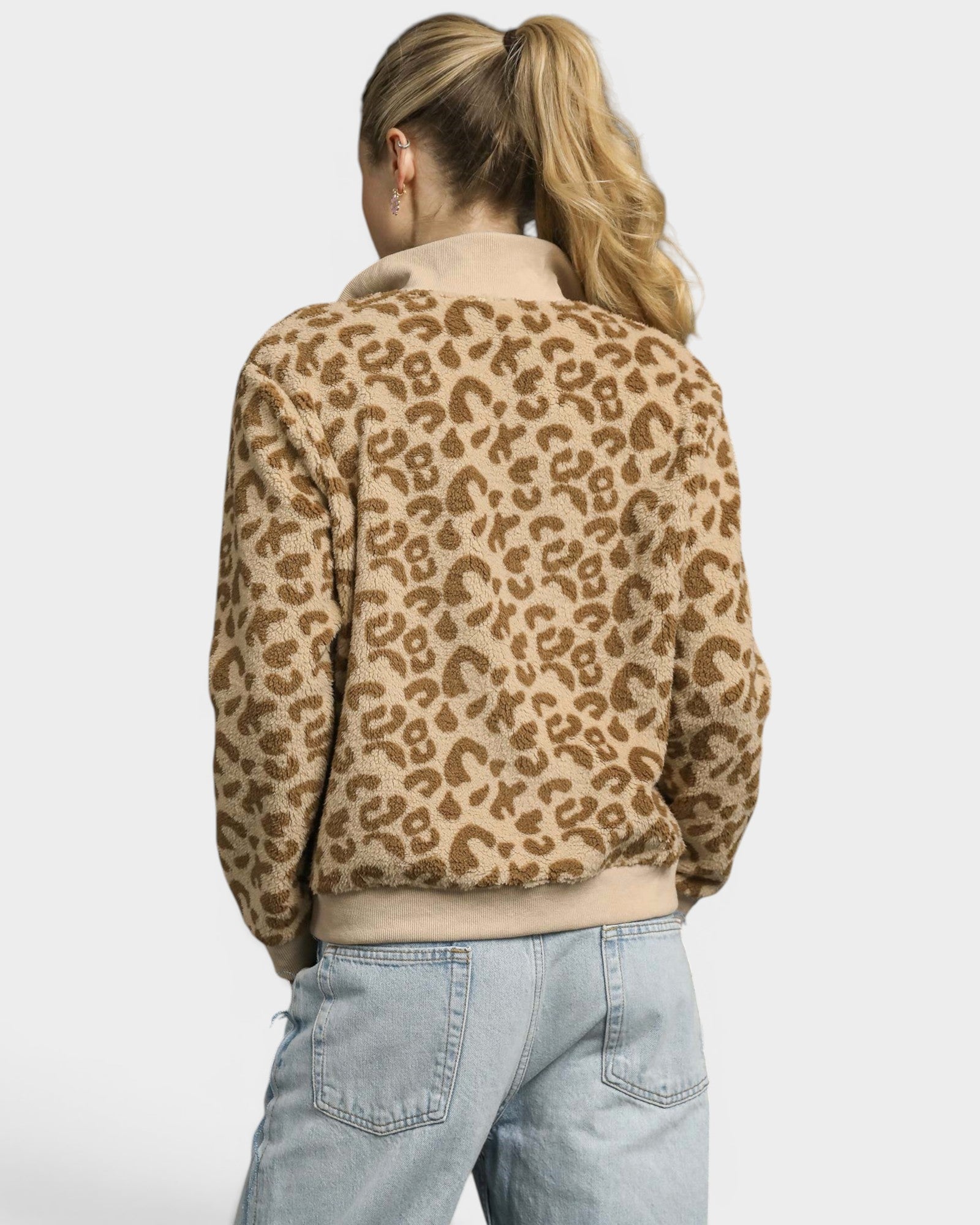 Person wearing a leopard print jacket and light blue jeans on a white background
