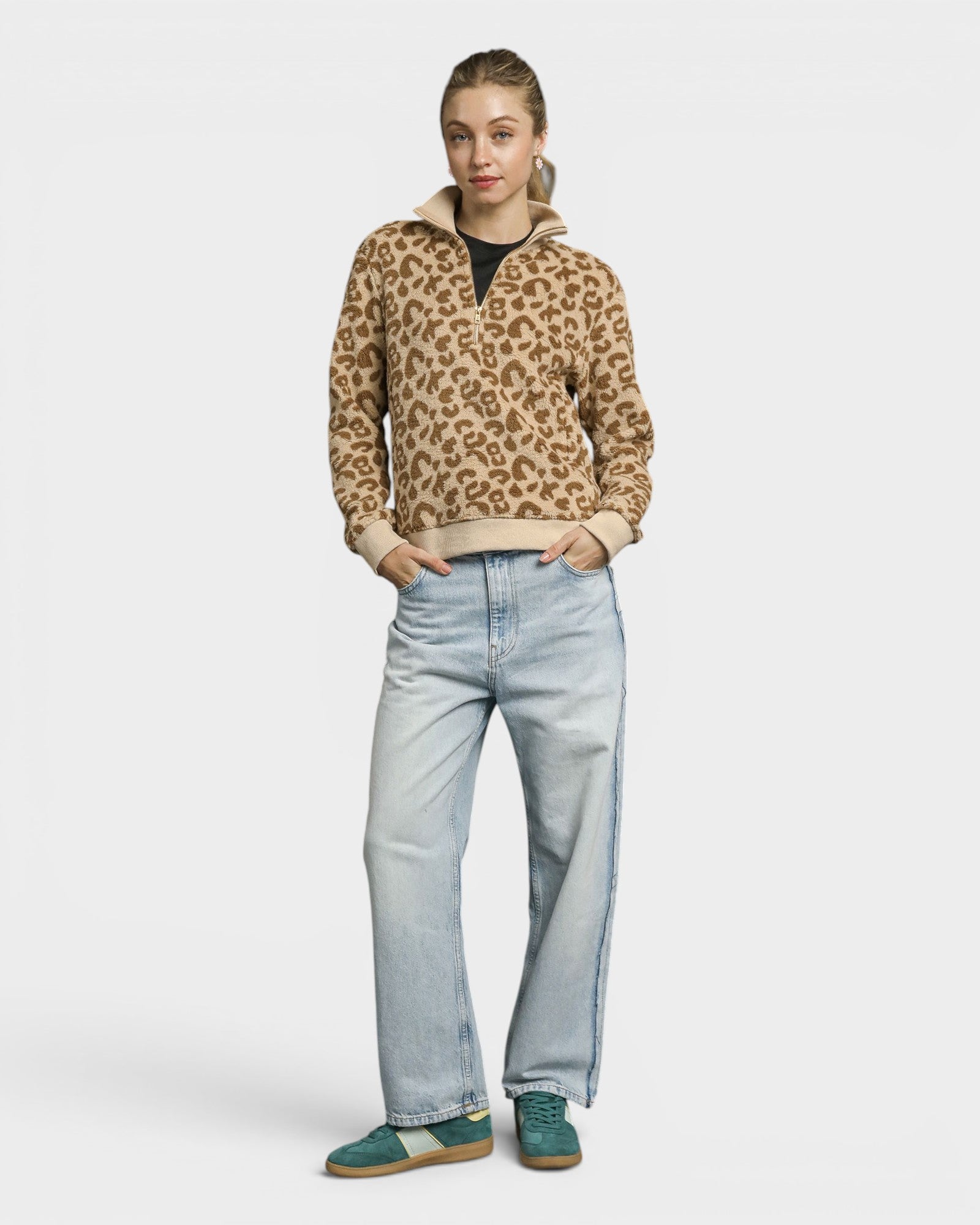Person wearing a leopard print sweater and light blue jeans on a white background