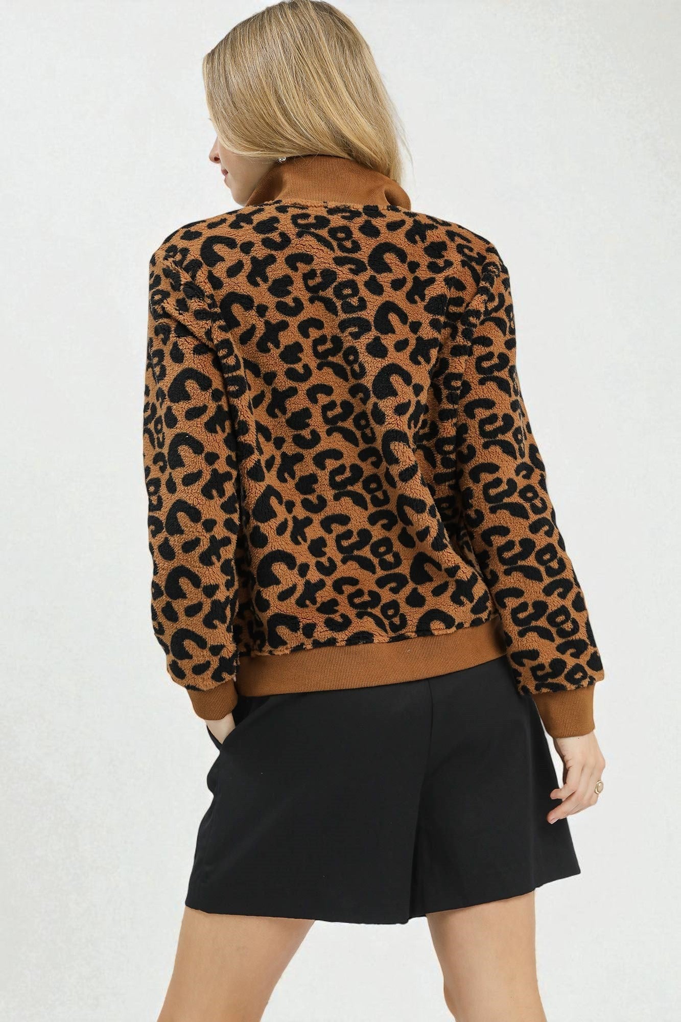 Person wearing a leopard print jacket and black shorts on a white background