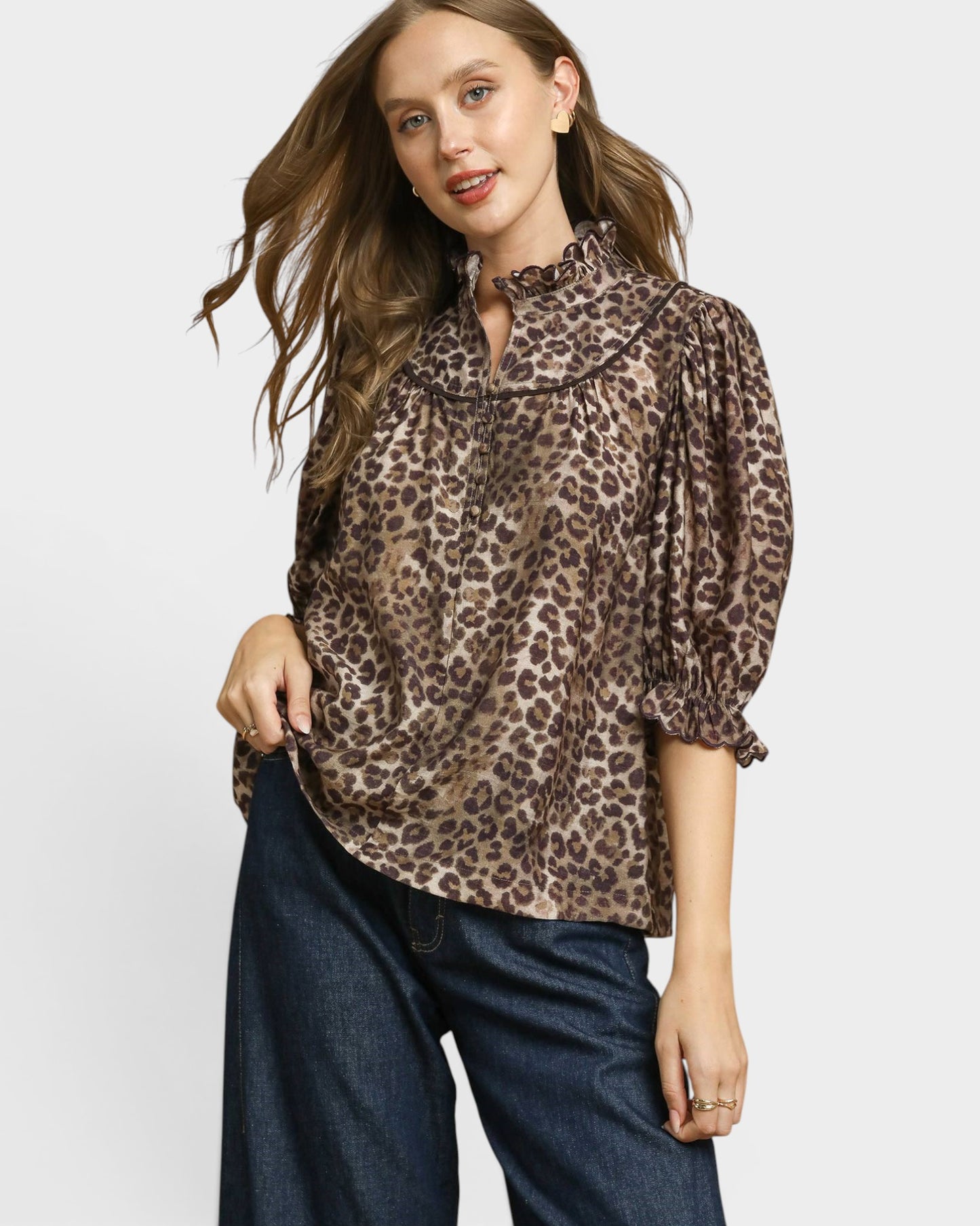 Woman wearing a leopard print blouse and blue jeans on a white background