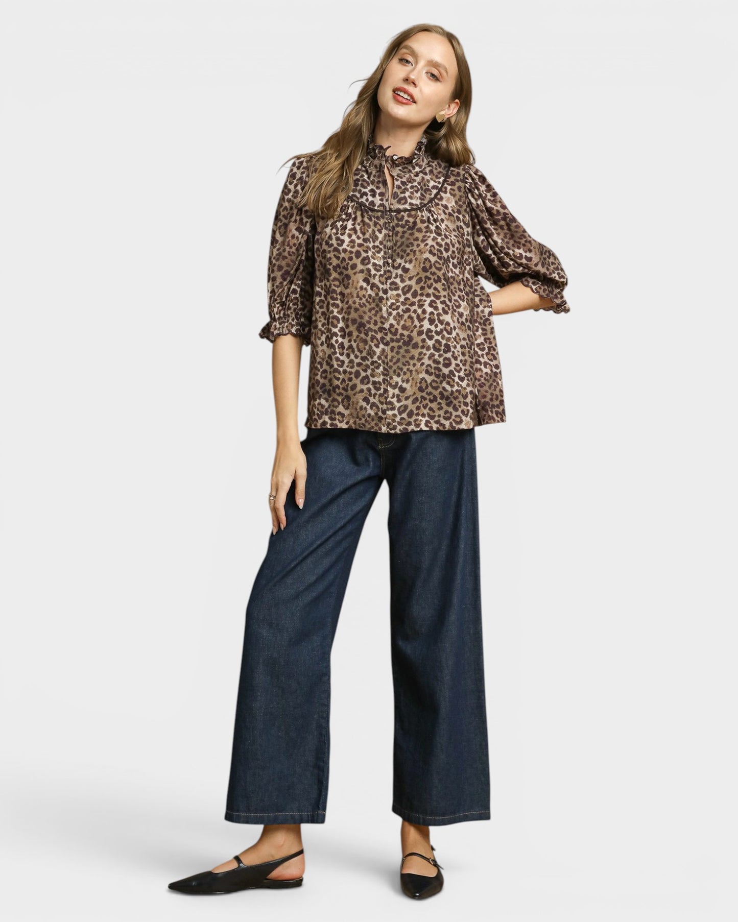 Woman wearing a leopard print blouse and blue jeans on a white background