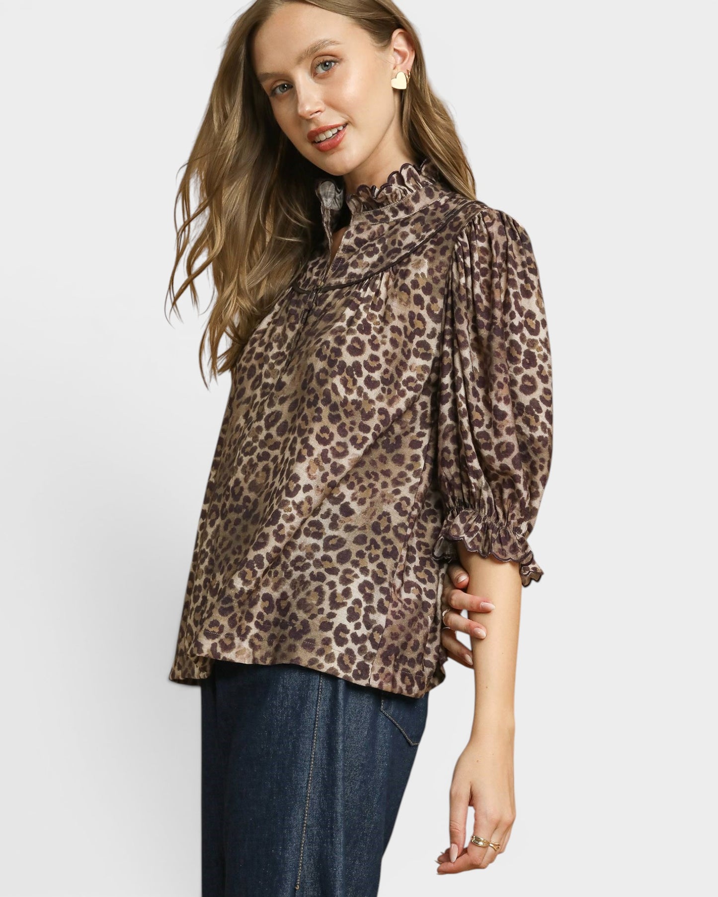 Woman wearing a leopard print blouse with long sleeves on a white background