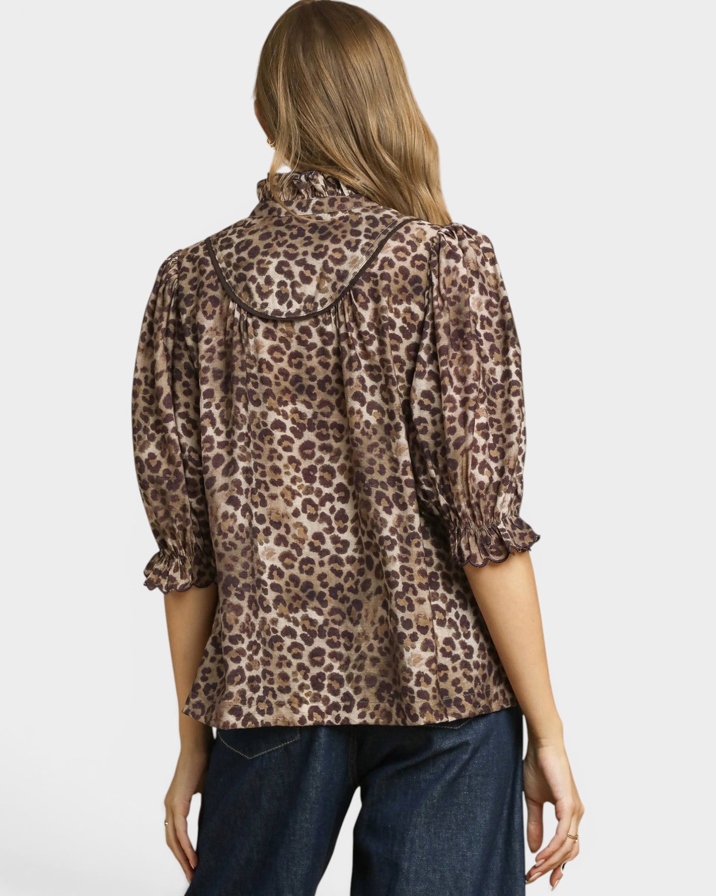 Woman wearing a leopard print blouse with a plain background
