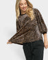 Woman wearing a leopard print top and black pants on a white background
