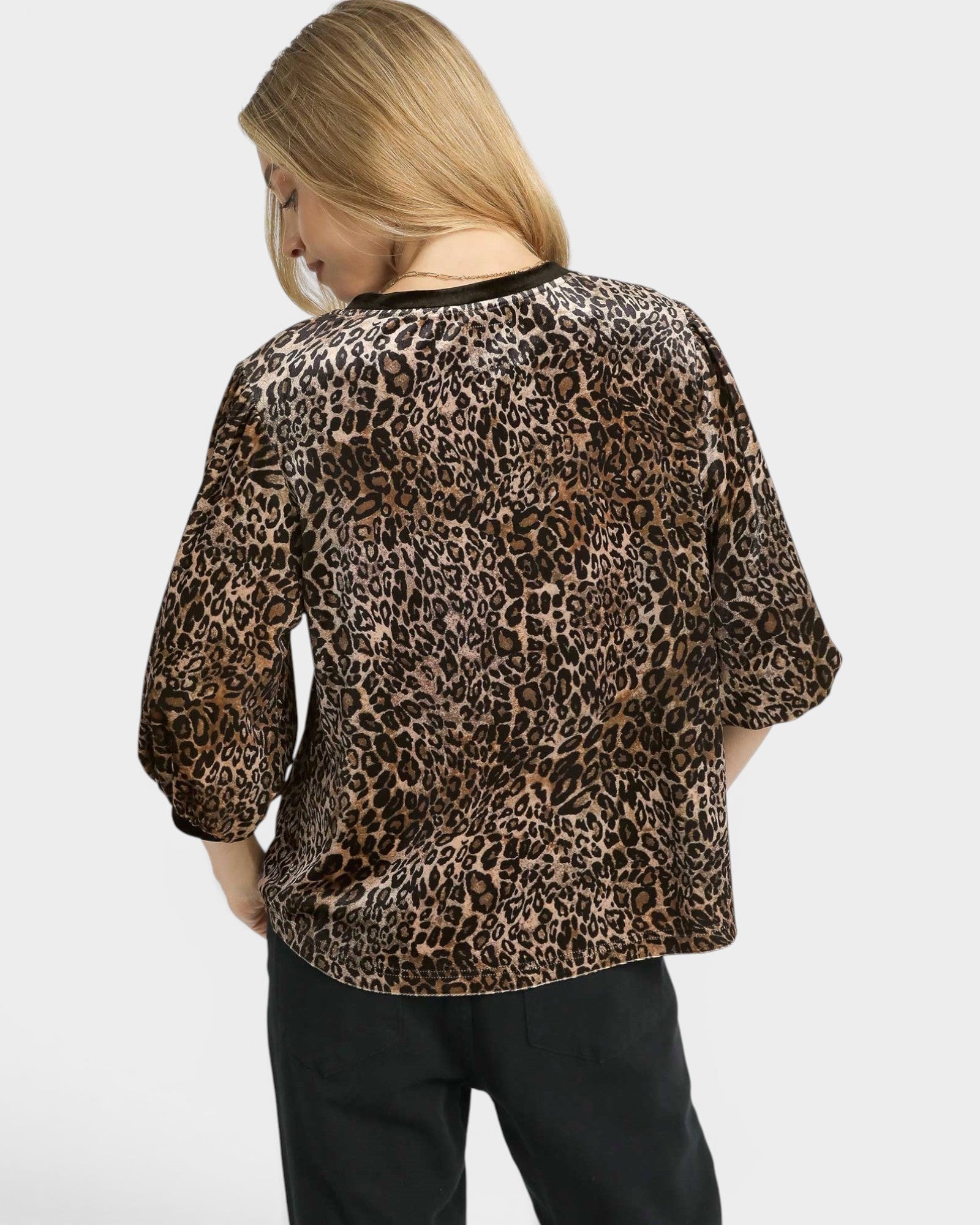 Person wearing a leopard print top on a plain background