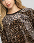 Person wearing a sheer leopard print top with a plain background