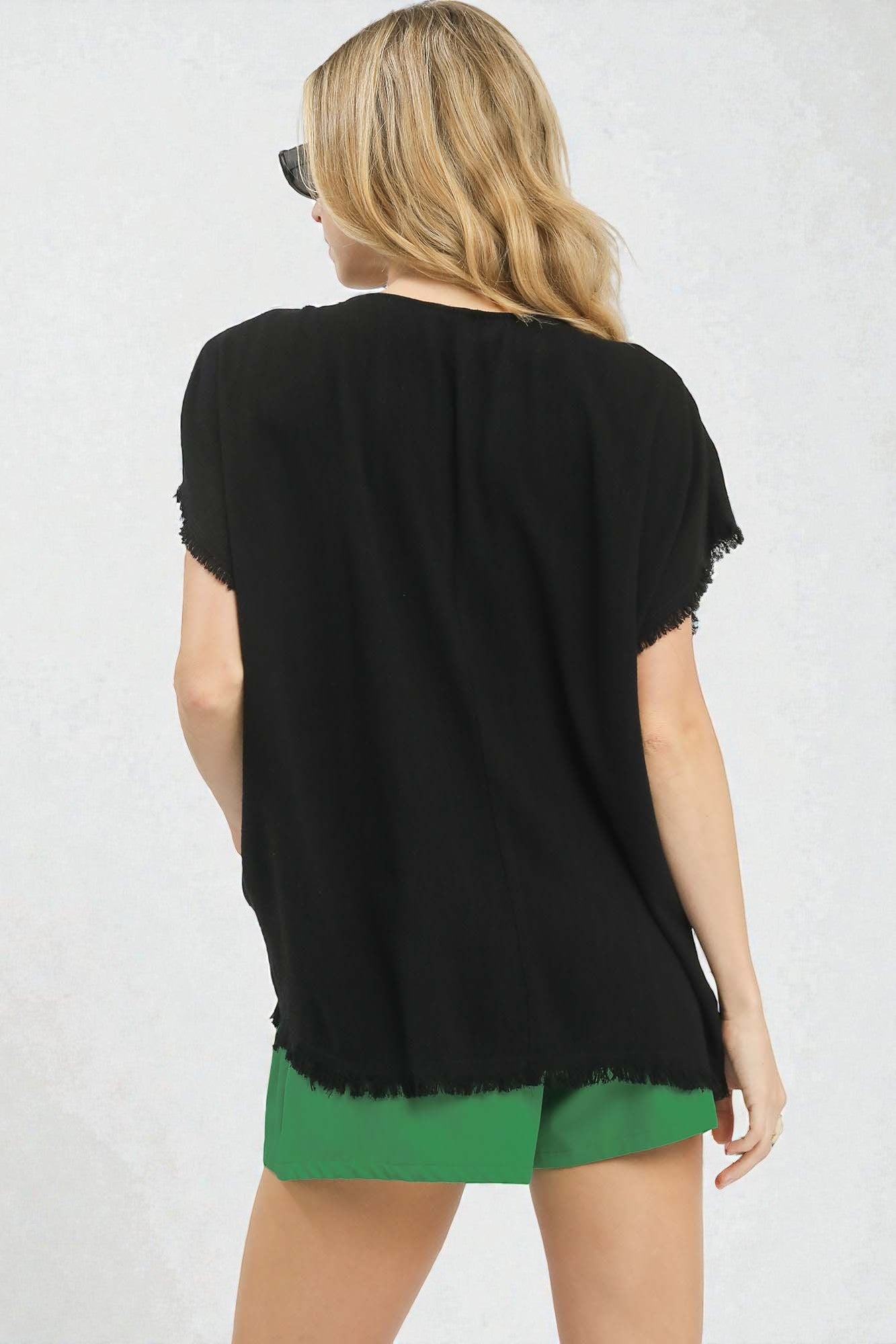 Woman wearing a black top and green shorts on a white background