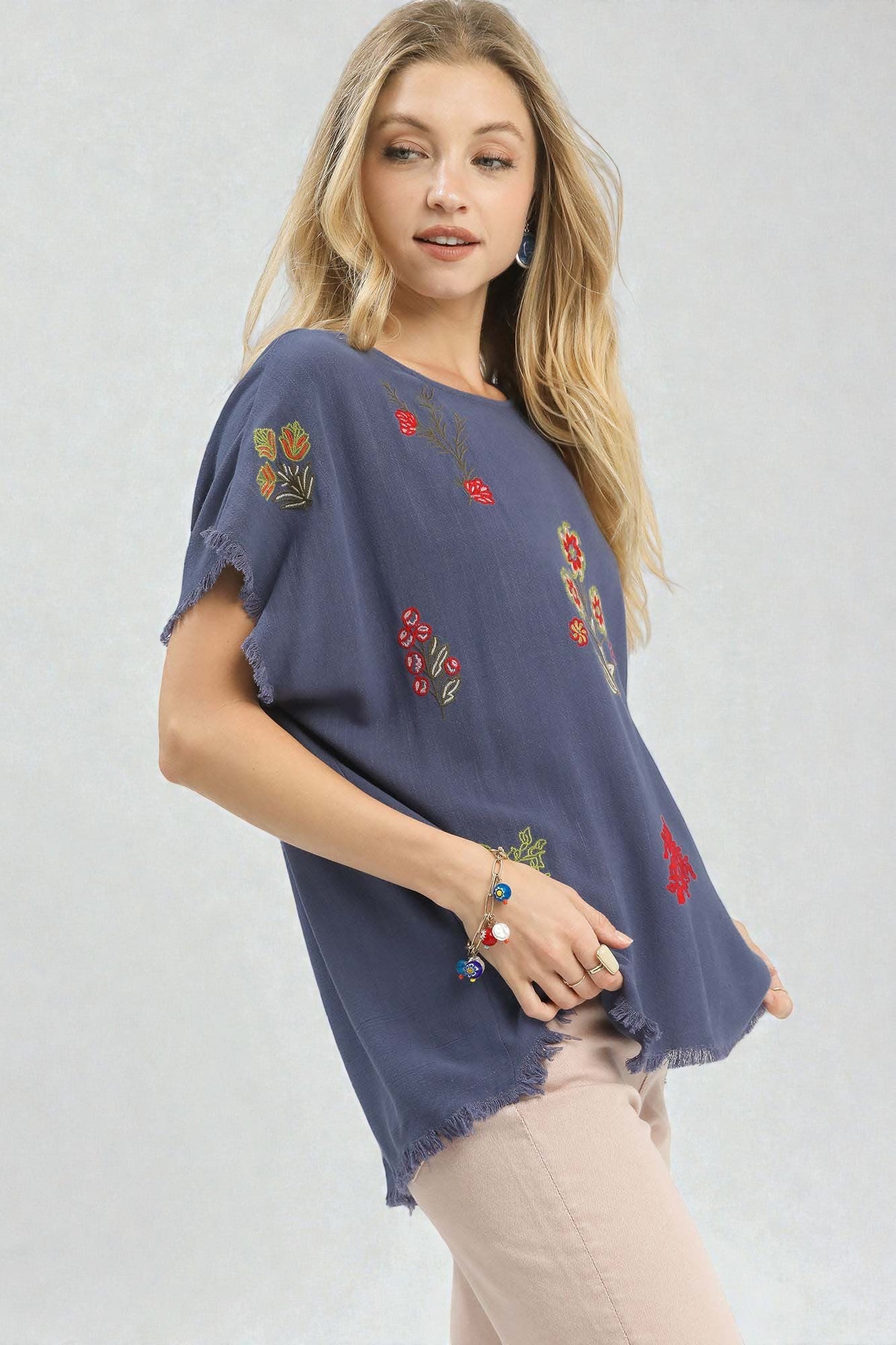 Woman wearing a blue embroidered top against a white background