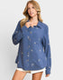 Woman wearing a blue shirt with white patterns on a plain background