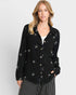 Woman wearing a black jacket with white patterns on a light gray background